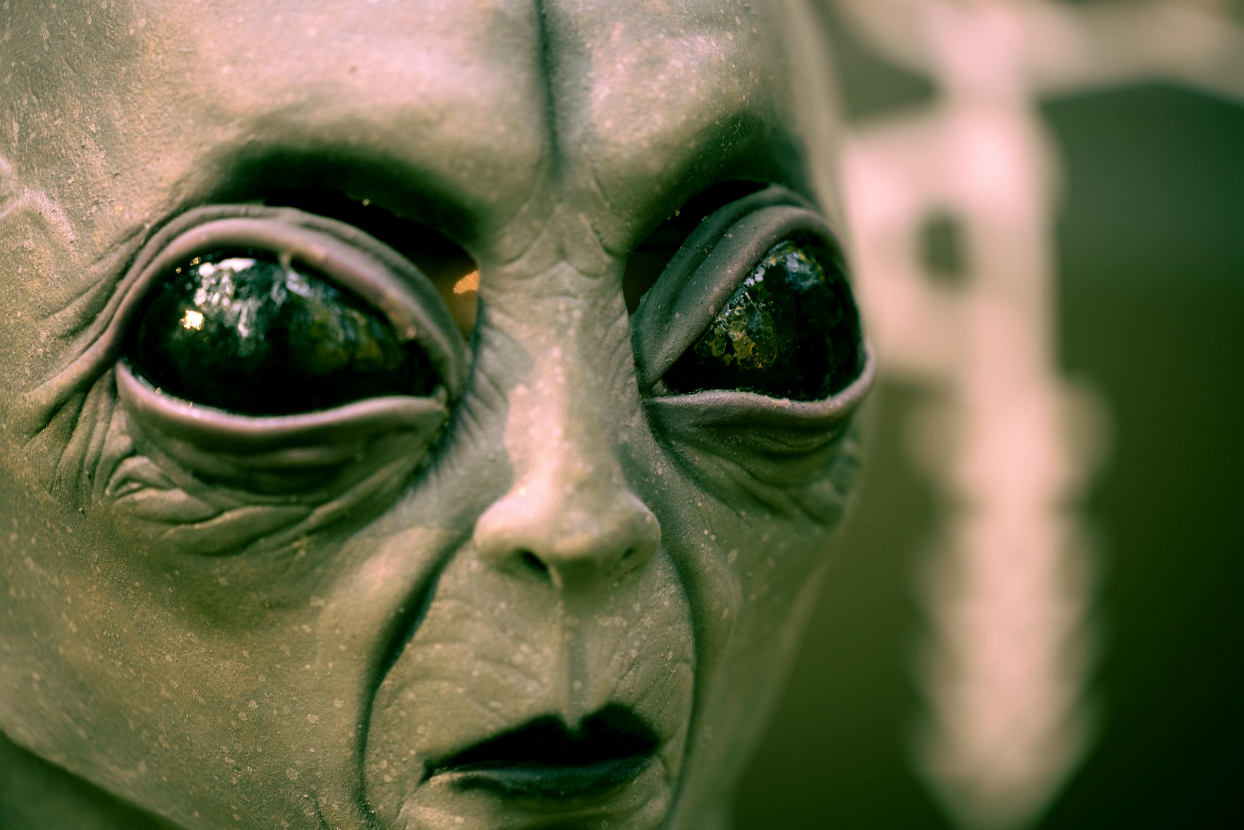 Detailed close-up of an alien face mask with black eyes, perfect for Halloween or sci-fi themes.