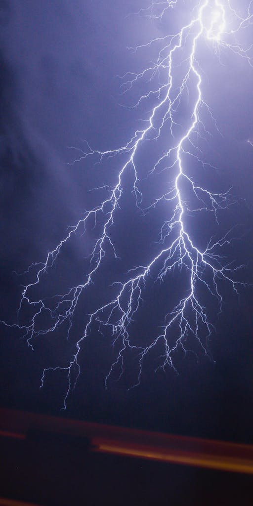 Intense lightning bolt illuminating a dark night sky during a powerful thunderstorm.