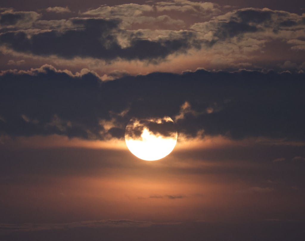 A captivating view of the full moon behind dense clouds during a twilight evening in Stamford, CT.