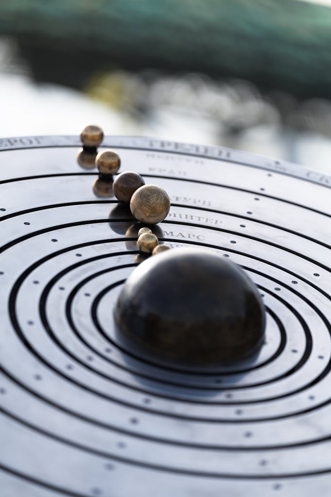 Abstract representation of the solar system in metal with Russian labels, photographed outdoors.